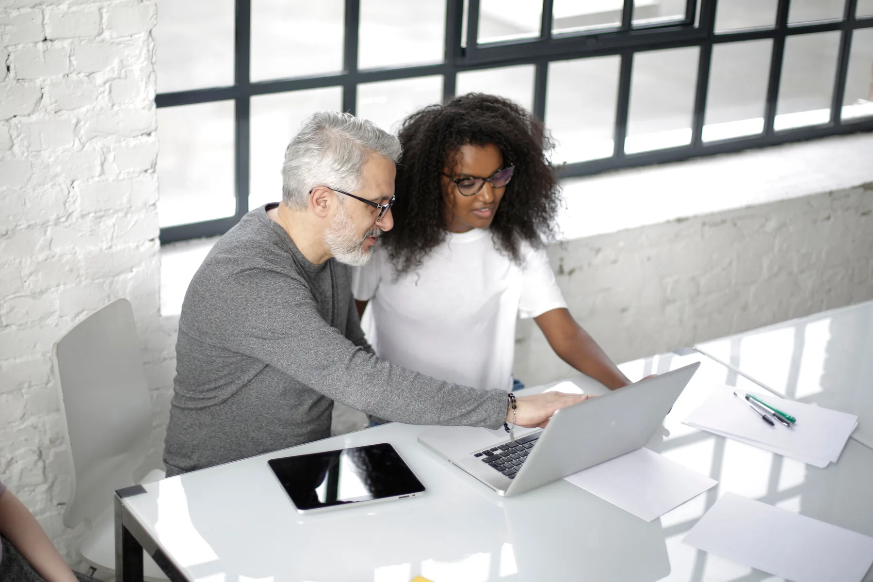 Twee professionals bespreken werk achter een laptop